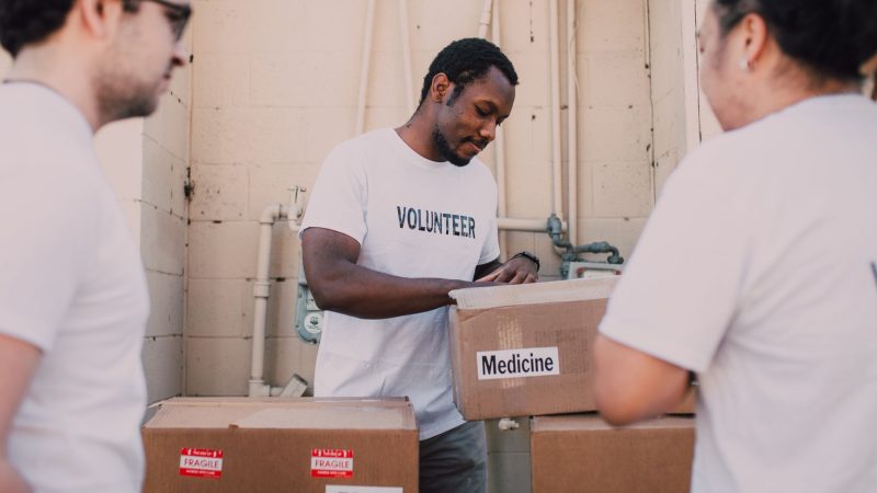 Volunteers packing food and medicine boxes for donation. Community service and support efforts.